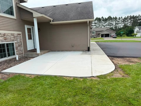 New concrete driveway and apron in front of a garage attached to a residential home with green lawn