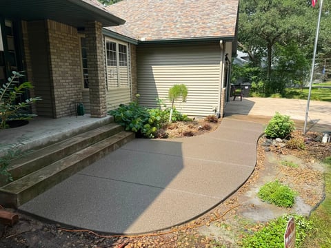 Brick house with curved concrete patio and landscaping including shrubs and topiary