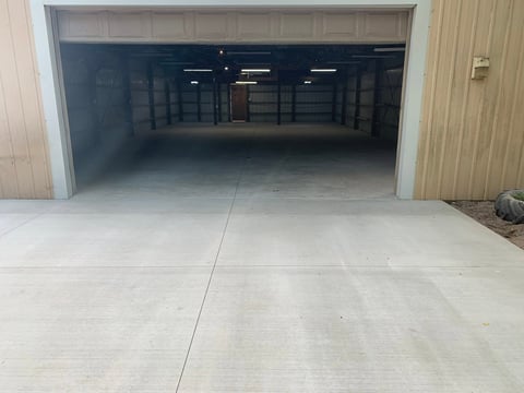 Empty garage interior with open black garage door and concrete driveway